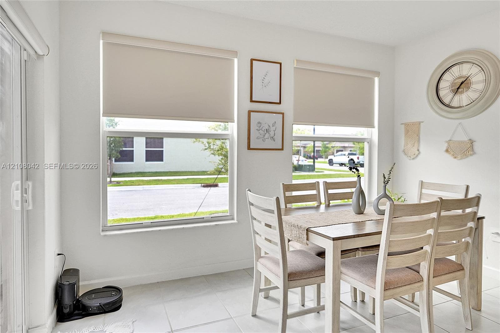 Neutral-toned space featuring large windows with roller shades, tile flooring, and a sliding glass door