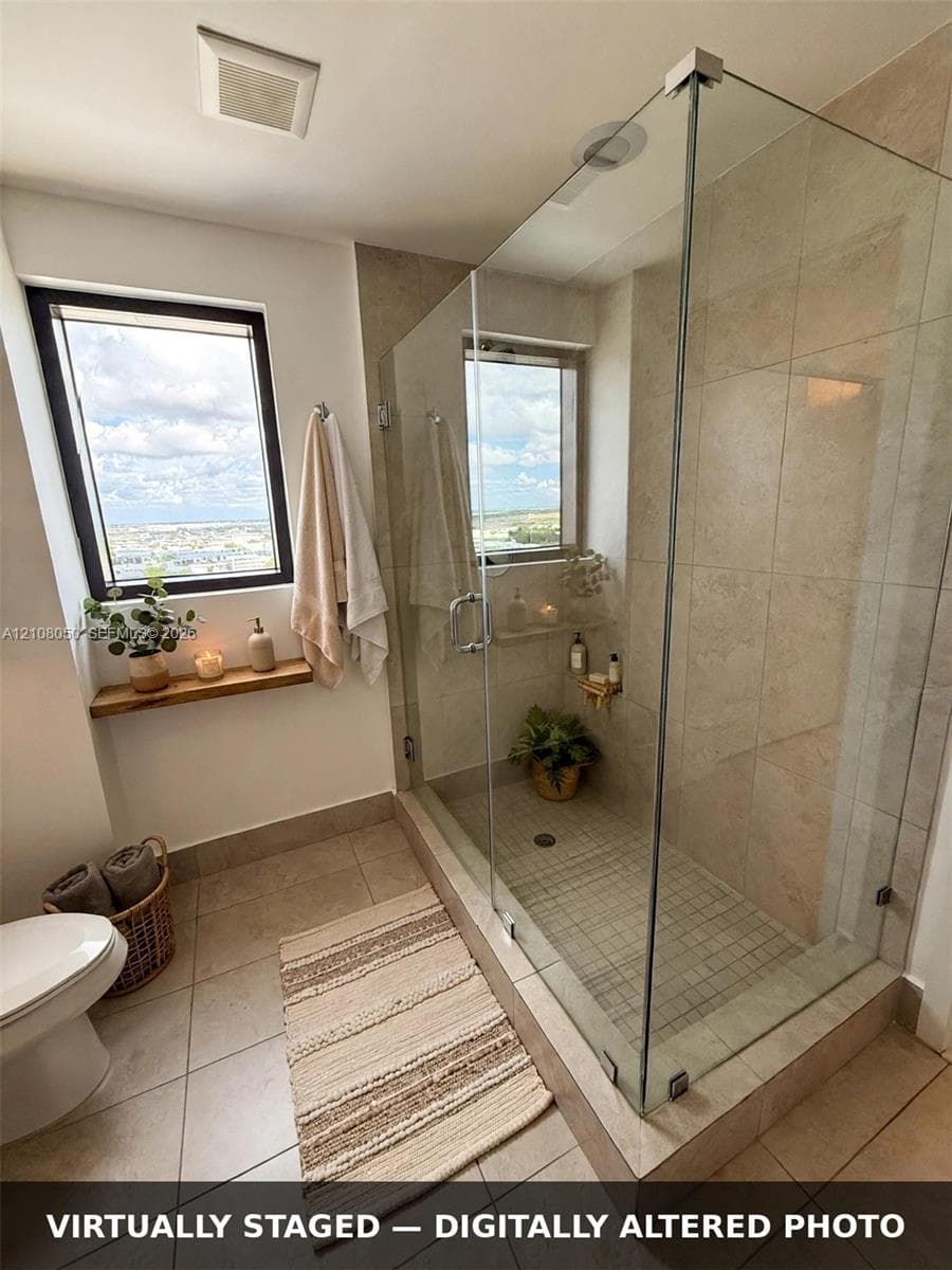 Walk-in shower with floor-to-ceiling neutral wall tile, mosaic tile flooring, and a frameless glass enclosure, featuring a wood-finish floating ledge and large windows