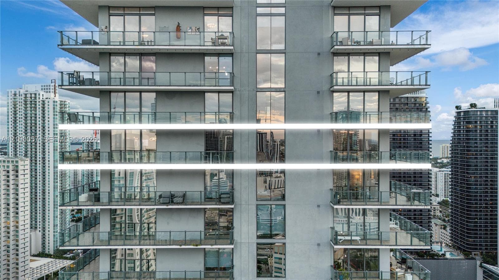 High-rise exterior featuring floor-to-ceiling glass windows and expansive cantilevered balconies with glass railings