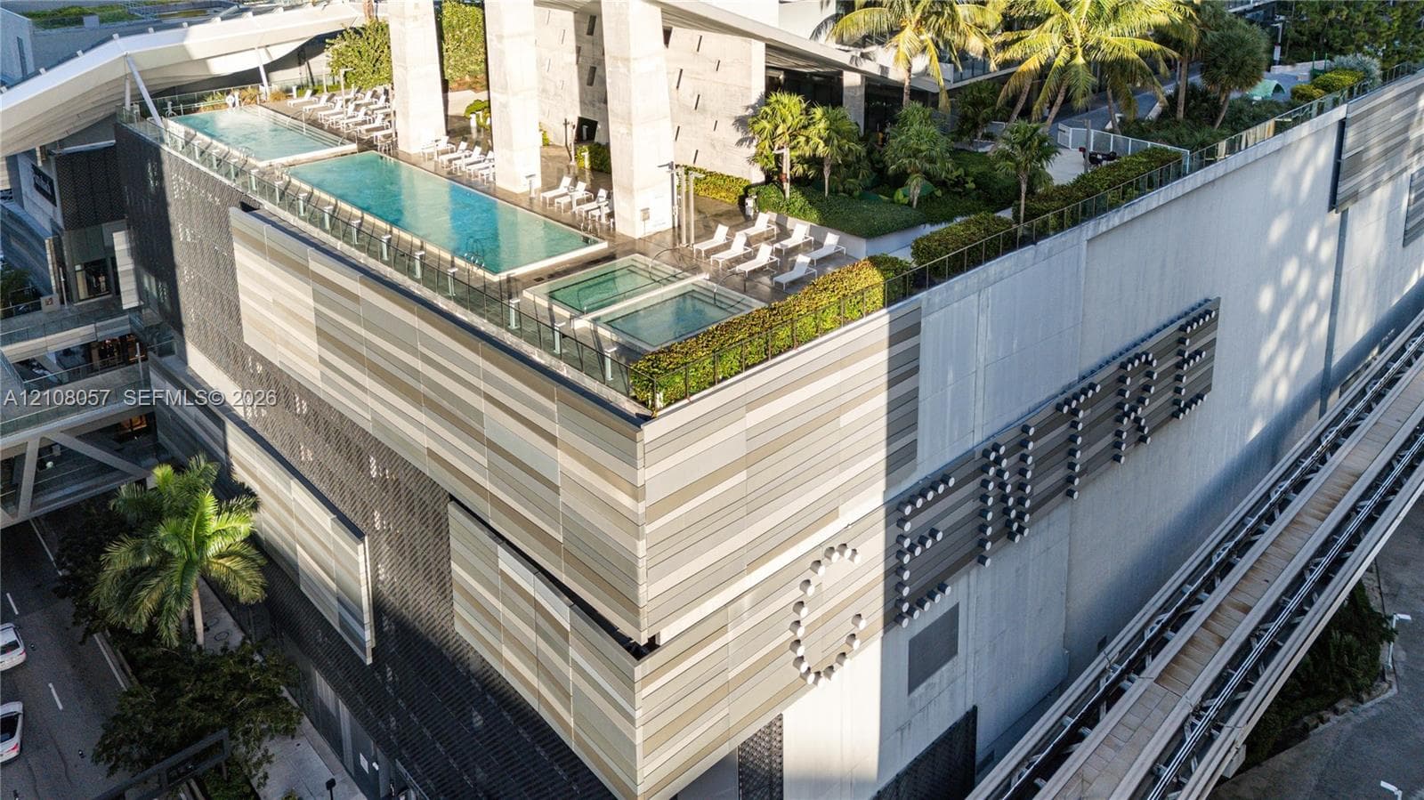Rooftop terrace featuring an elevated swimming pool, spa, manicured landscaping, and contemporary panelized building facade