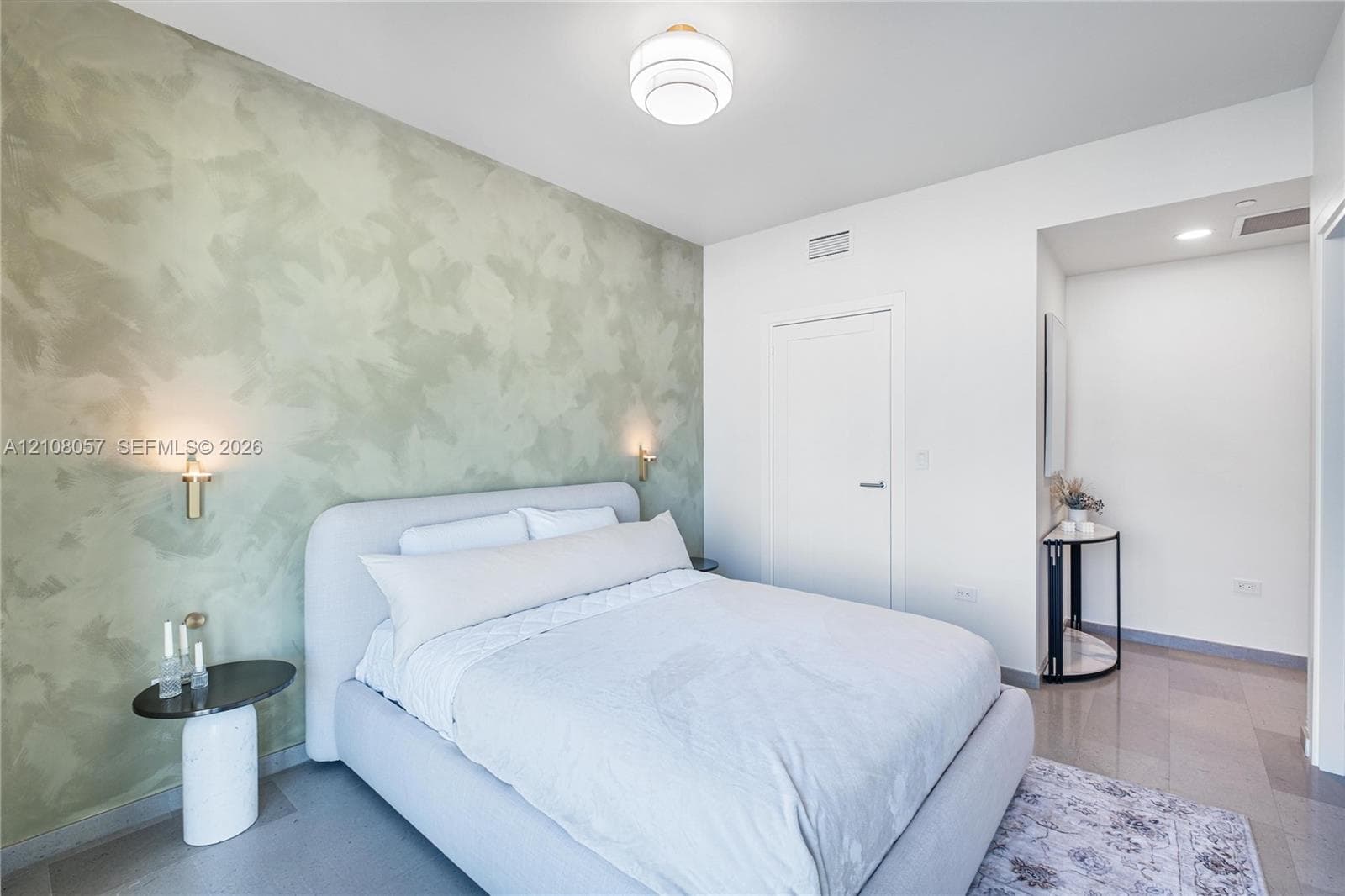 Custom textured green accent wall, spherical ceiling mount light fixture, and dual gold-toned wall sconces