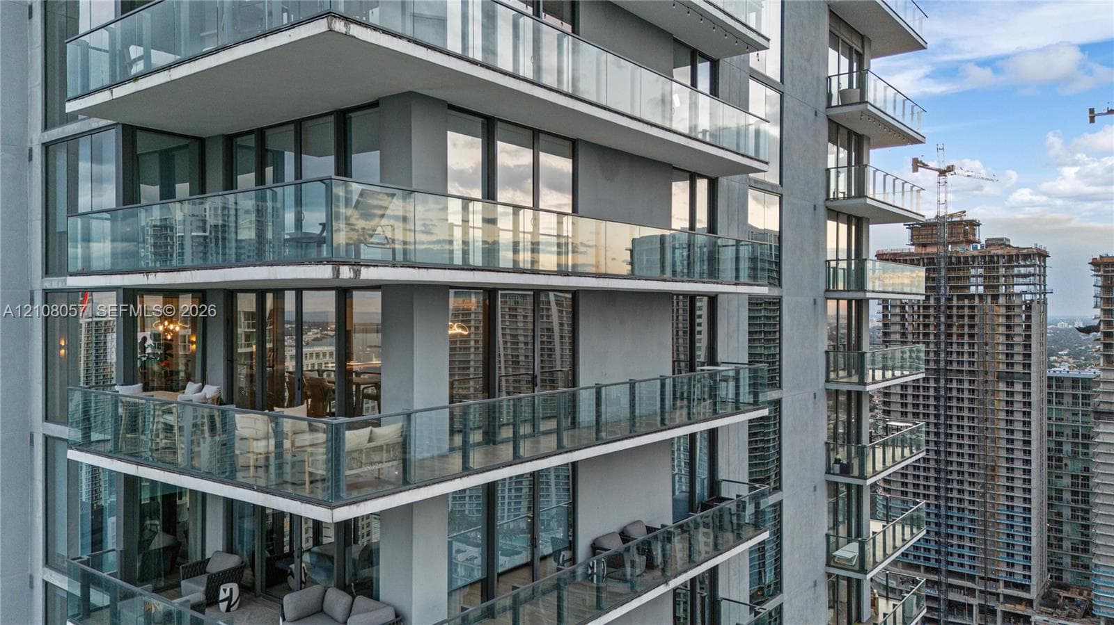 High-rise exterior featuring floor-to-ceiling glass windows and multiple cantilevered private balconies with frameless glass railings