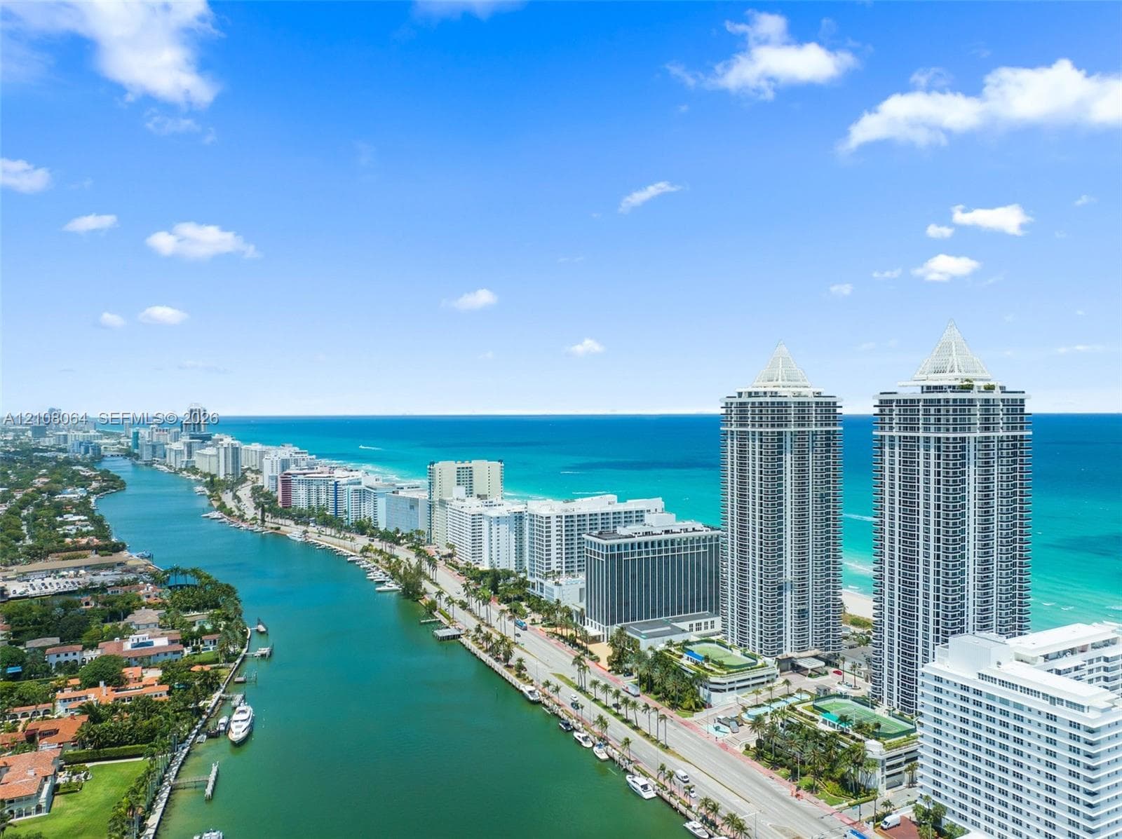 Aerial perspective featuring high-rise towers, proximity to the coastline, and a deep-water canal