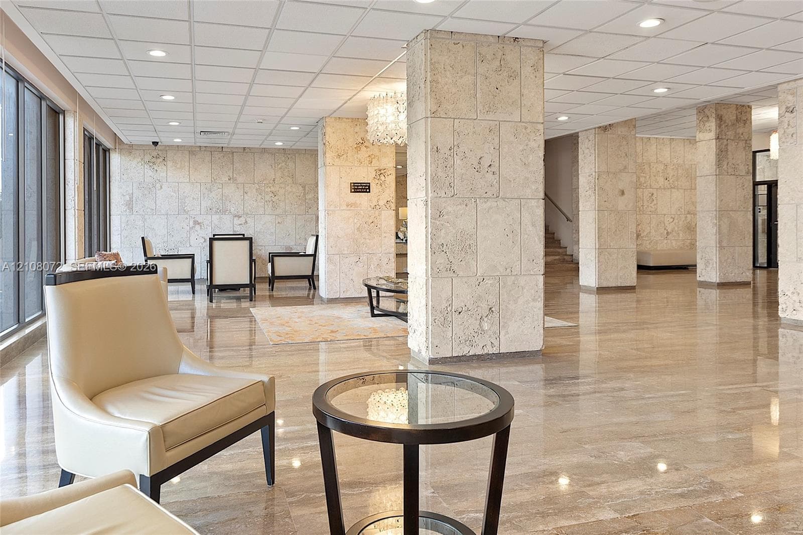 Lobby featuring polished stone flooring, floor-to-ceiling stone-clad structural columns, and recessed lighting throughout a drop ceiling