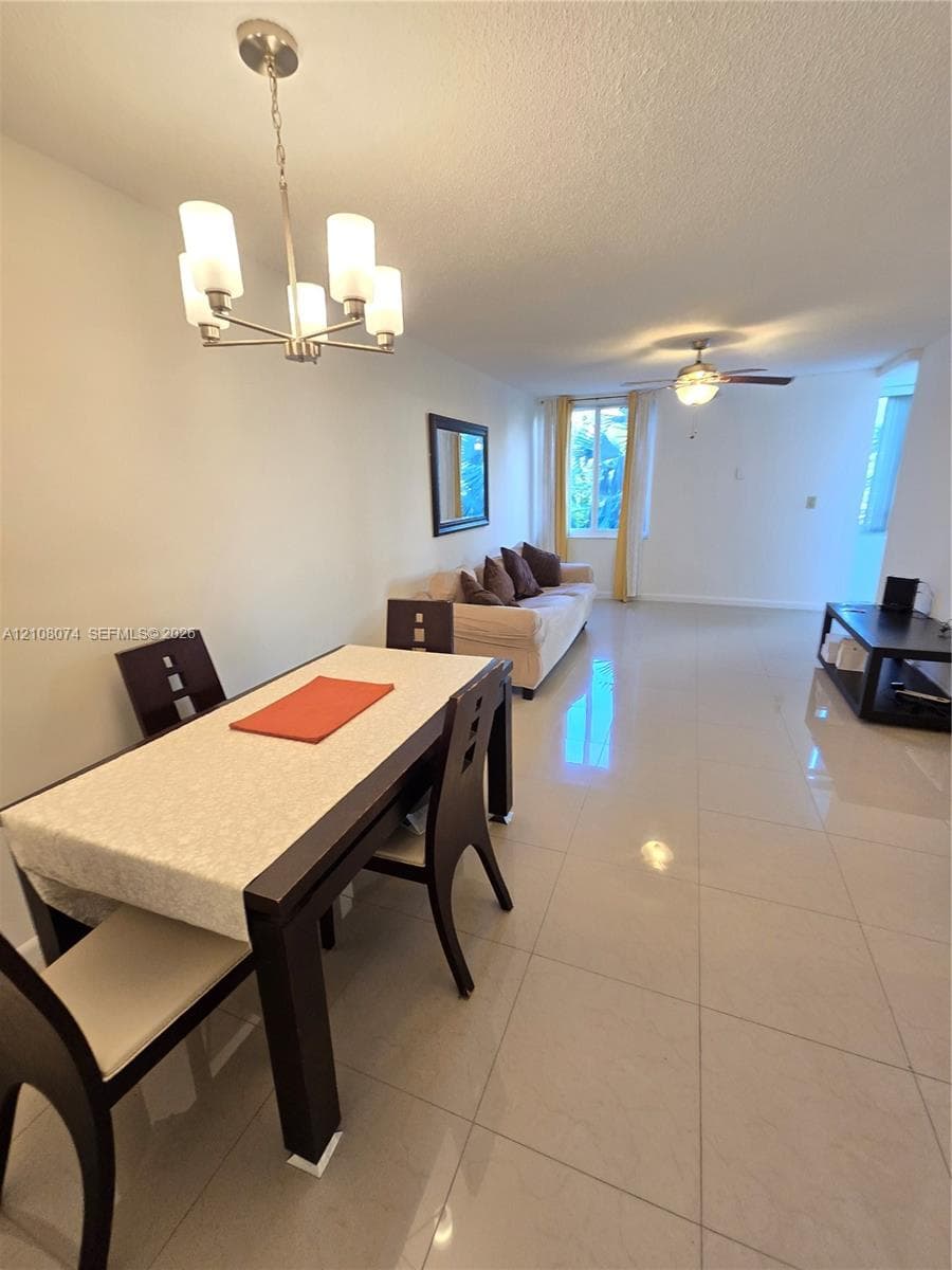 Large-format tile flooring, multi-light chandelier, and ceiling fan with integrated lighting