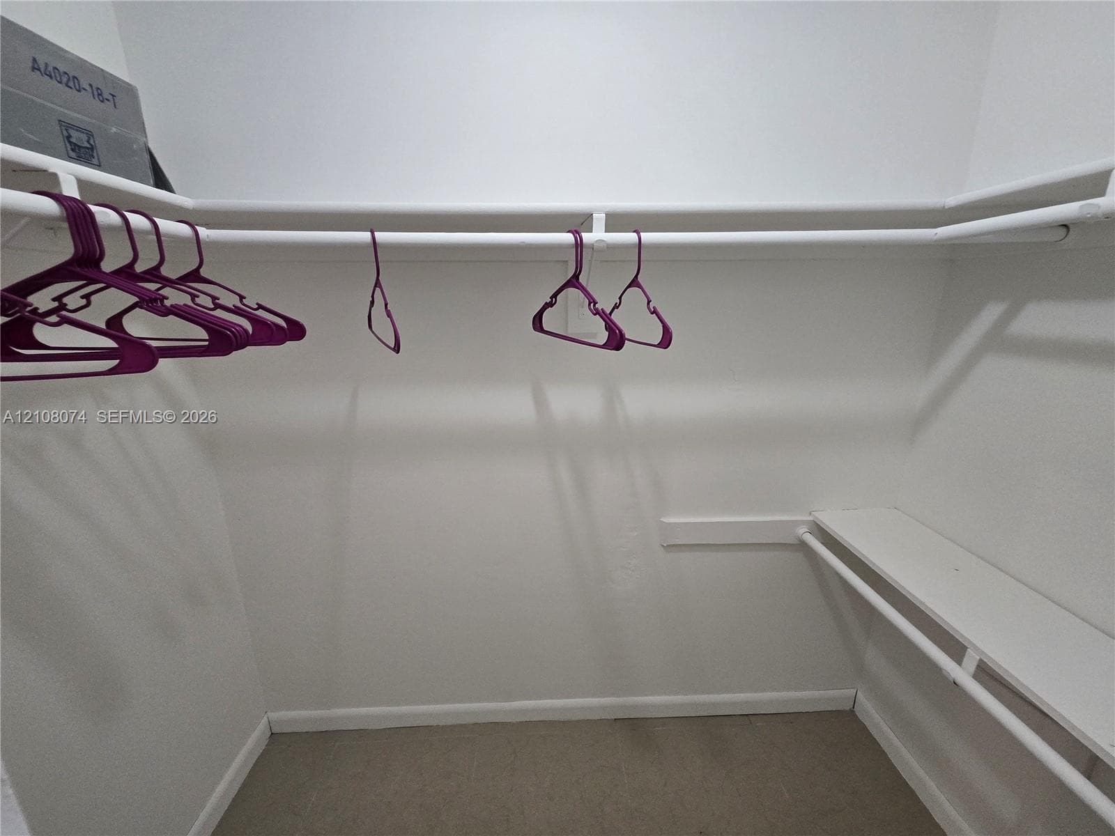 Walk-in closet featuring white wall-mounted shelving and dual-tier clothing rods