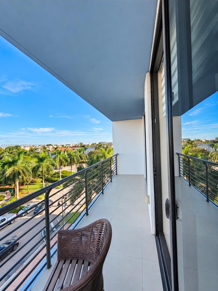 Covered balcony featuring large-format tile flooring, metal horizontal-bar railing, and floor-to-ceiling glass sliding doors