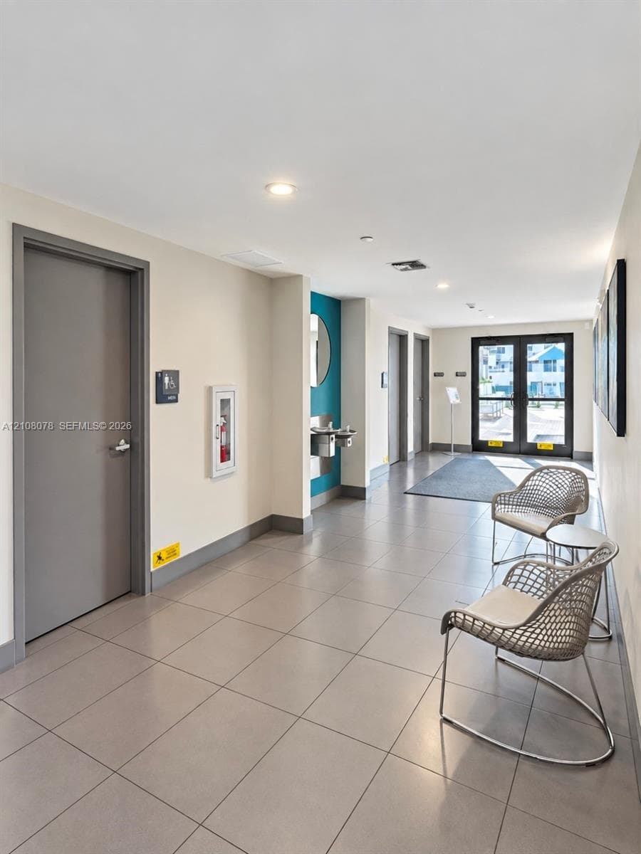 Common area featuring large-format ceramic tile flooring, recessed LED lighting, and metal-framed double glass entry doors