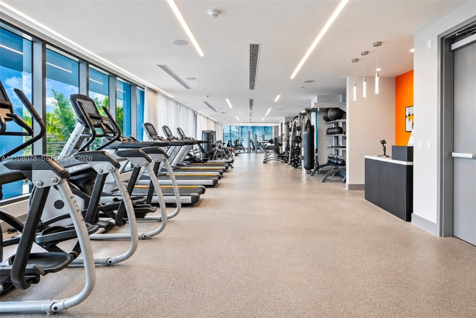Fitness center featuring floor-to-ceiling windows, linear recessed lighting, durable composite flooring, and built-in service cabinetry