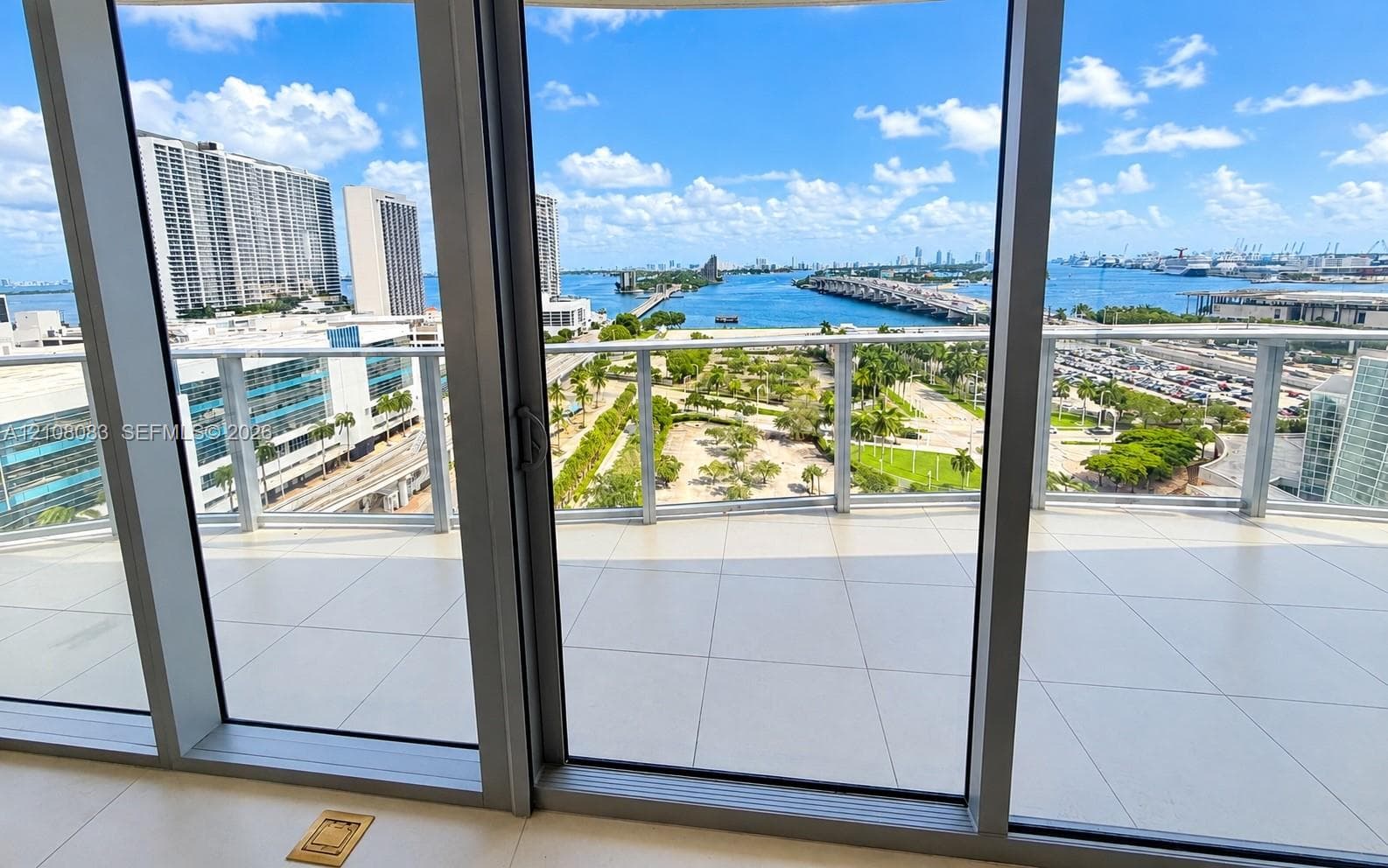Covered balcony with large-format tile flooring, metal railing, and floor-to-ceiling glass doors
