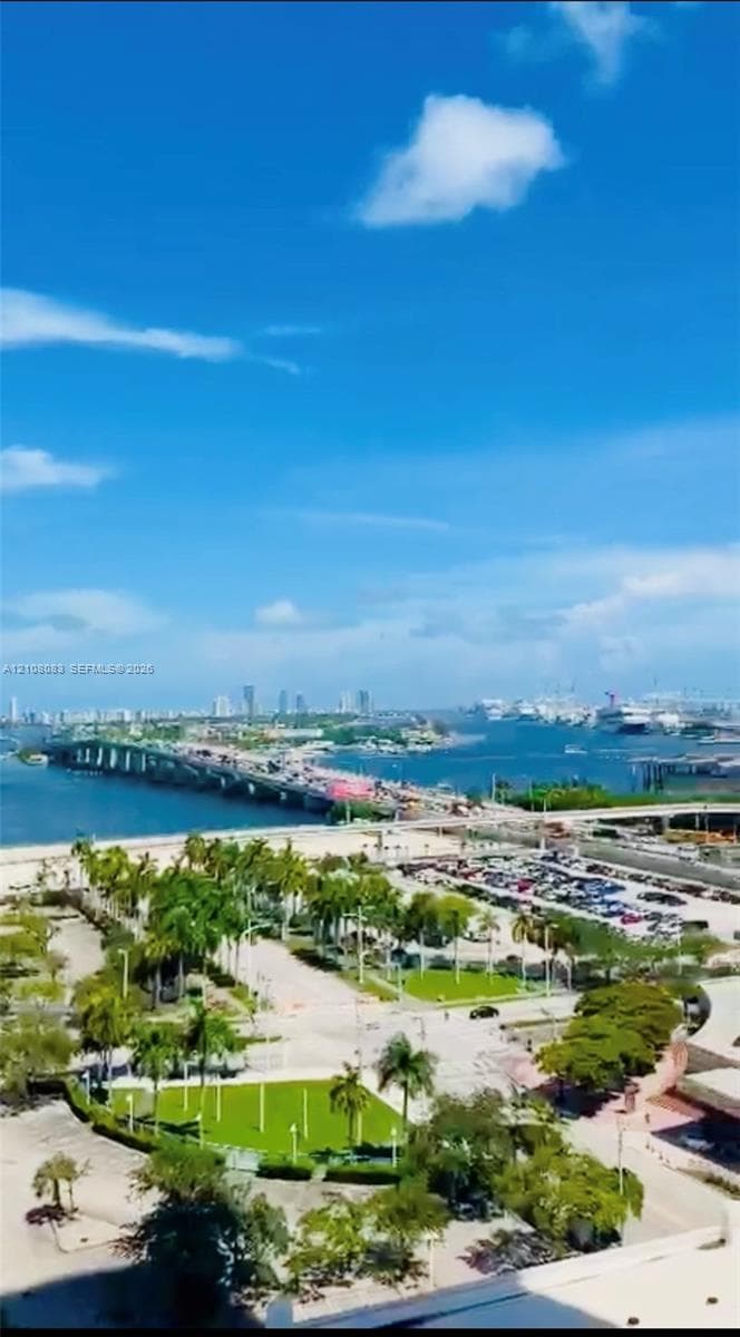 Elevated perspective featuring coastal waters, a causeway, harbor boat traffic, and mature palm trees