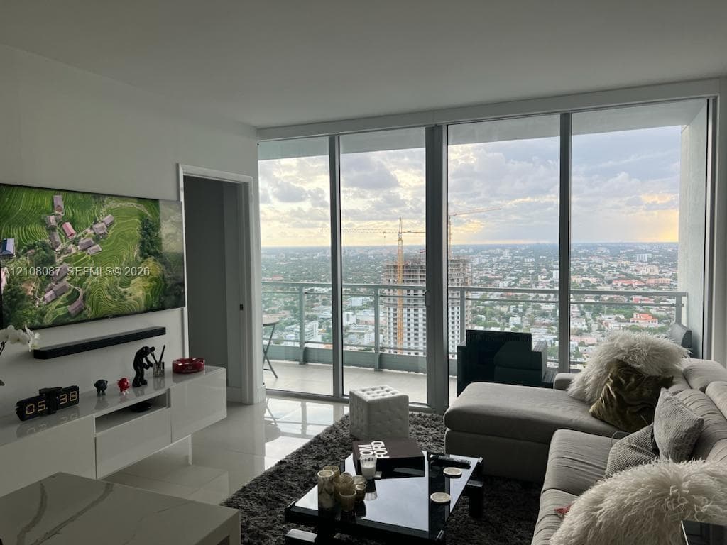 Floor-to-ceiling windows, private balcony with metal railing, and high-gloss white built-in cabinetry