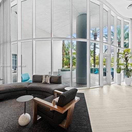 Curved floor-to-ceiling glass wall, light-toned stone tile flooring, and integrated structural column