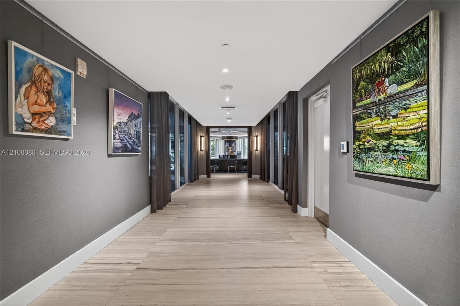 Wide corridor featuring large-format tile flooring, floor-to-ceiling windows with integrated drapery tracks, and recessed LED ceiling lighting