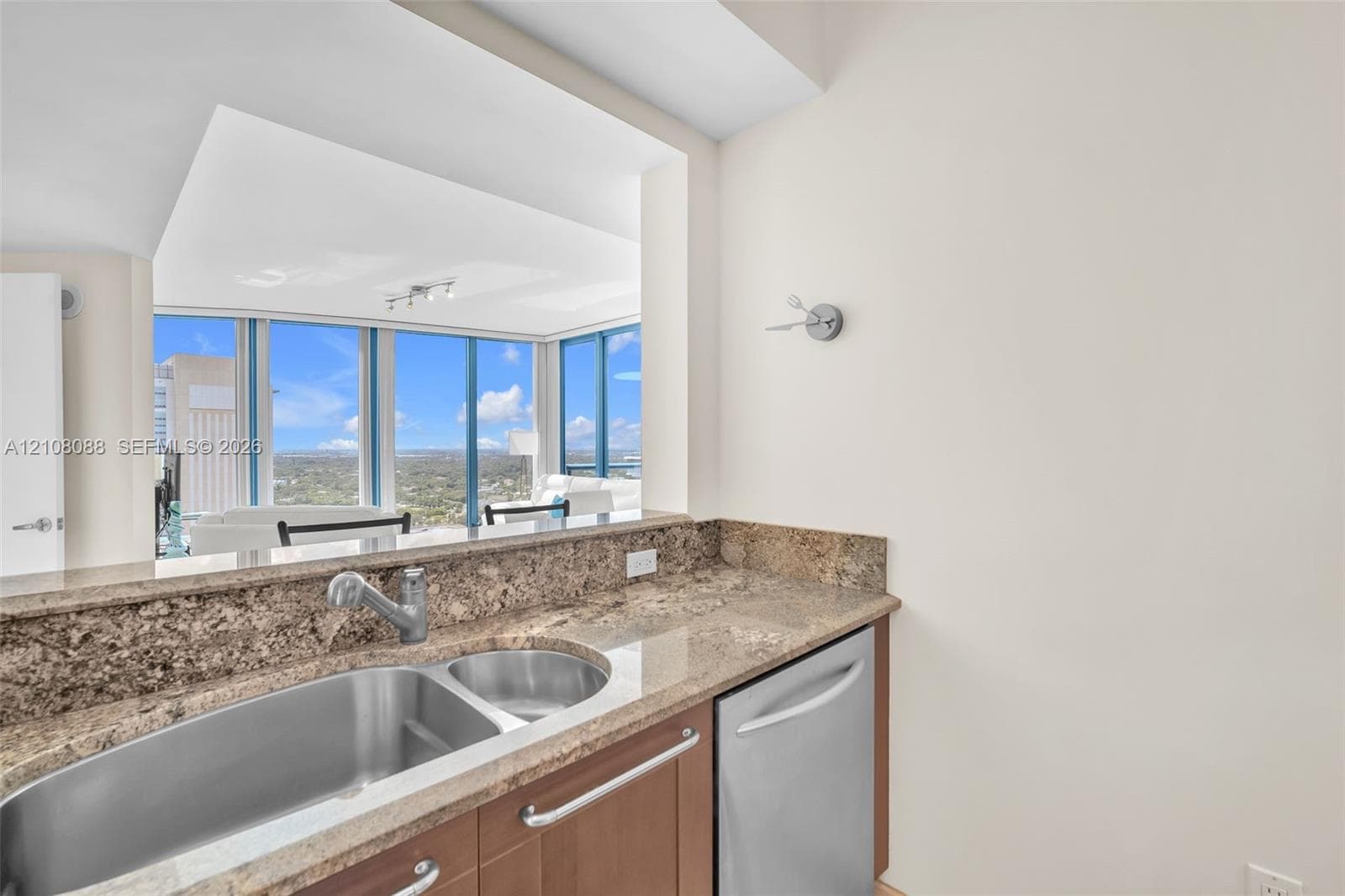 Kitchen featuring stone countertops, stainless steel dual-basin sink, high-arc faucet, built-in dishwasher, and wood cabinetry