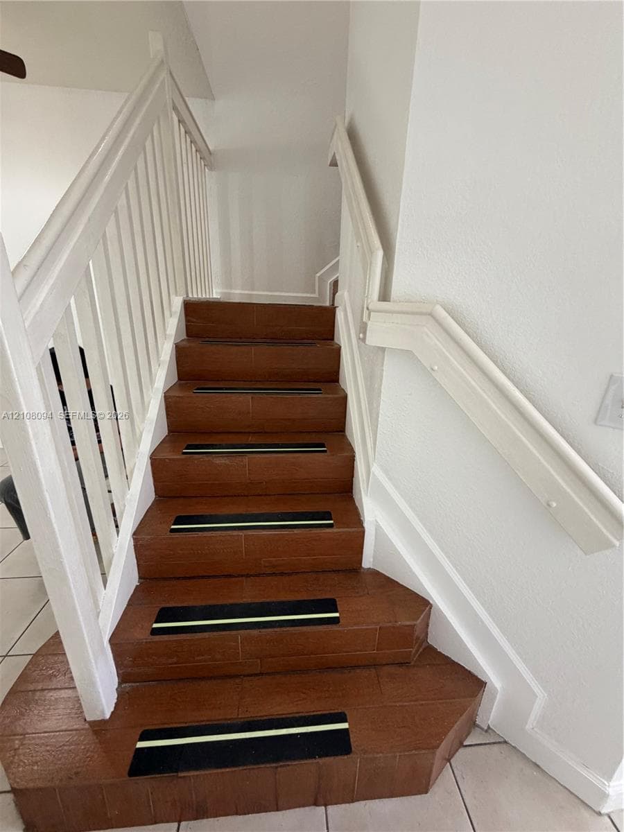 Staircase featuring wood-finish treads, white painted railing, and integrated non-slip step strips