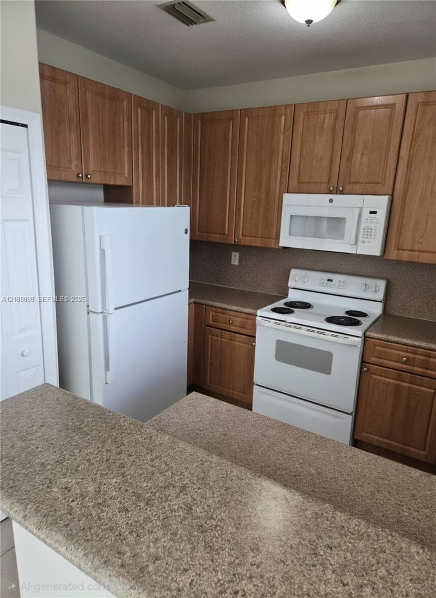 Kitchen featuring wood-finish cabinetry, solid surface countertops, white refrigerator, white electric range, and integrated over-the-range microwave