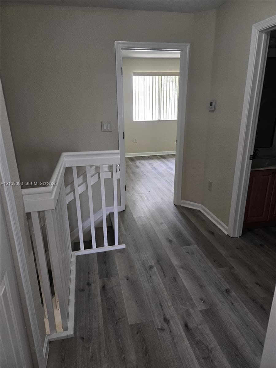 Hallway featuring wood-finish flooring, white wooden stair railings, and solid core interior doors