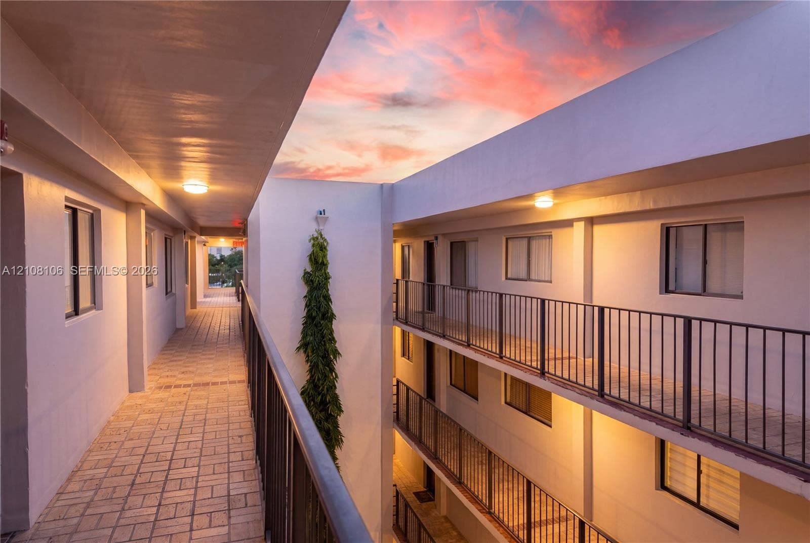 Exterior corridors featuring paver flooring, multi-level metal railings, and integrated recessed ceiling lighting