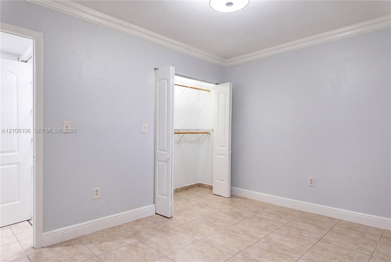 Ceramic tile flooring, crown molding, and a closet with bifold doors and built-in shelving