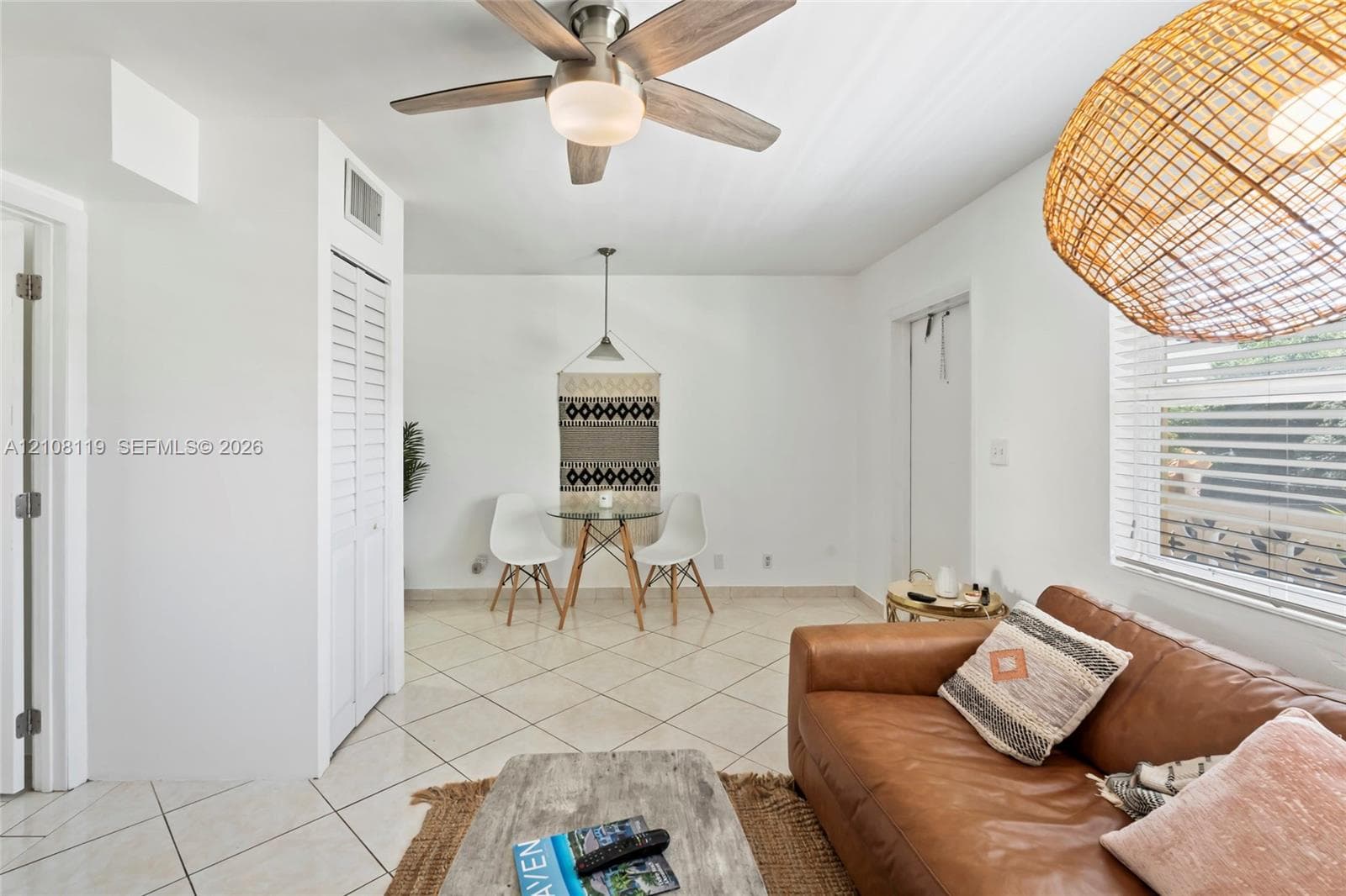 Large-format tile flooring, ceiling fan with integrated lighting, louvered bi-fold closet doors, and horizontal slat window blinds