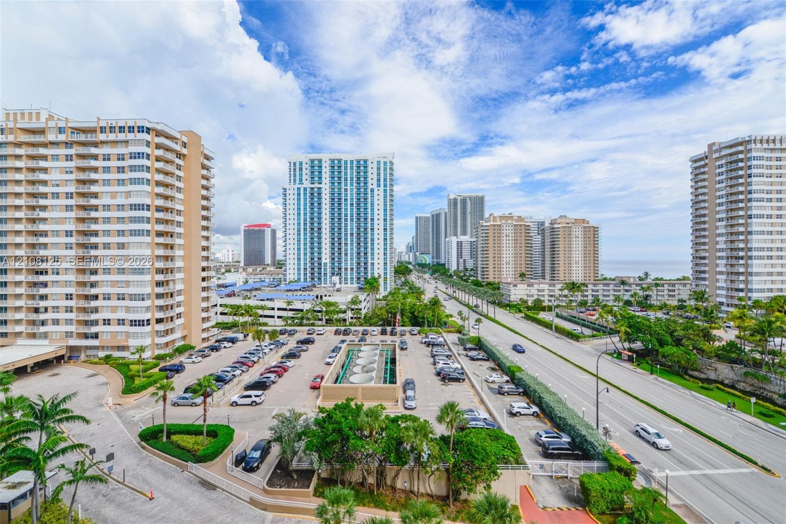 High-rise urban setting featuring paved surface parking, mature palm trees, multi-story residential structures, and proximity to major roadways