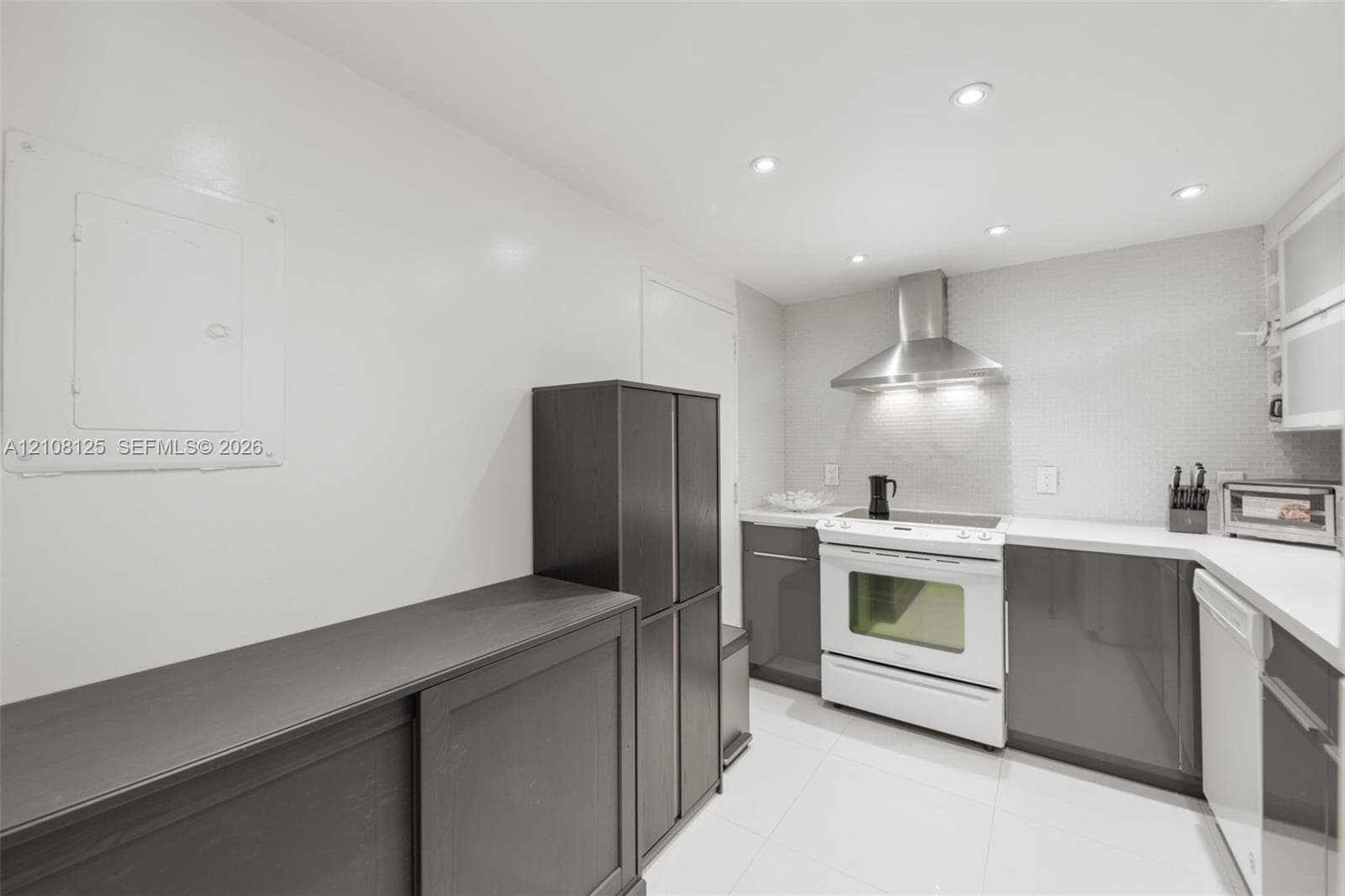 Kitchen featuring dark-toned cabinetry, white countertops, stainless steel range hood, built-in range, and recessed ceiling lighting