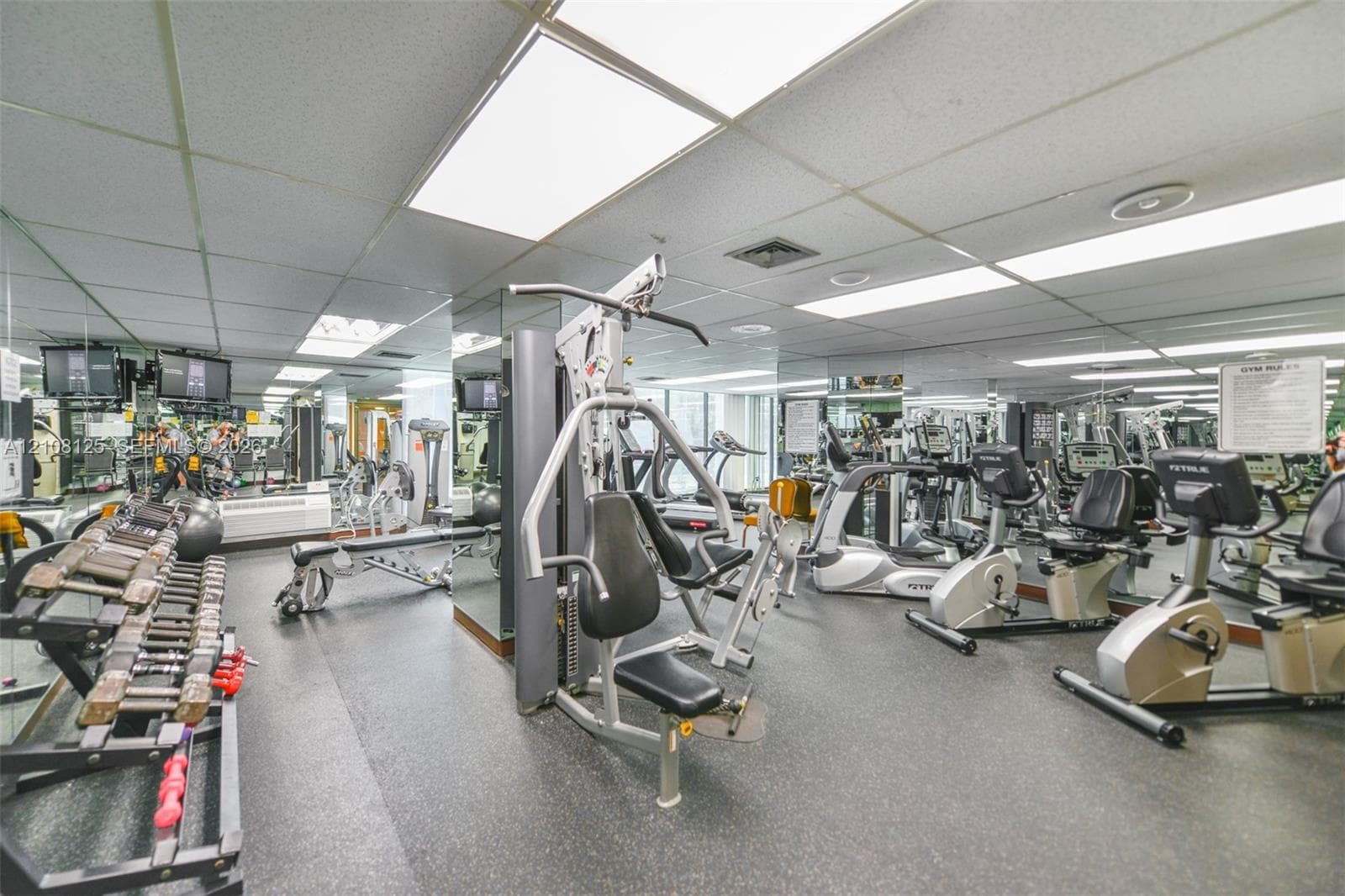 Fitness center featuring mirrored walls, resilient flooring, and recessed ceiling lighting