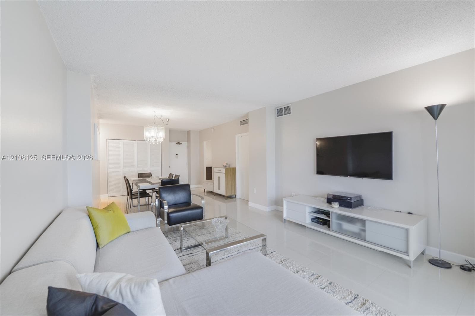 Open-concept living space featuring high-gloss tile flooring, neutral wall tones, and a crystal chandelier
