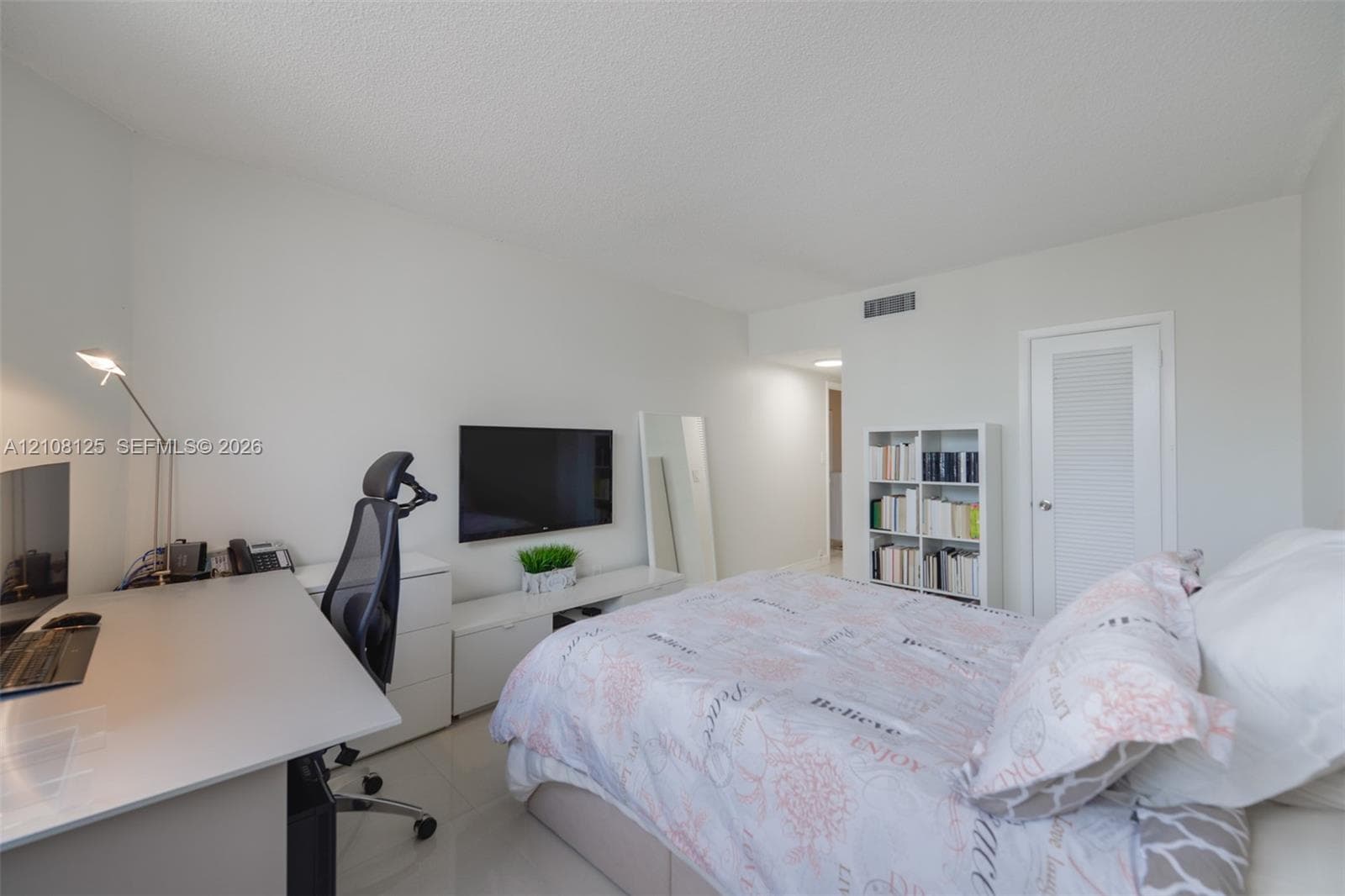 Neutral interior room featuring white walls, tile flooring, and a single-panel door with a louvered detail