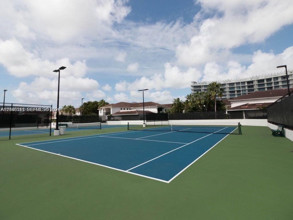Hard-surface tennis courts featuring high-pole lighting, perimeter fencing, and dual-tone blue and green court surfacing