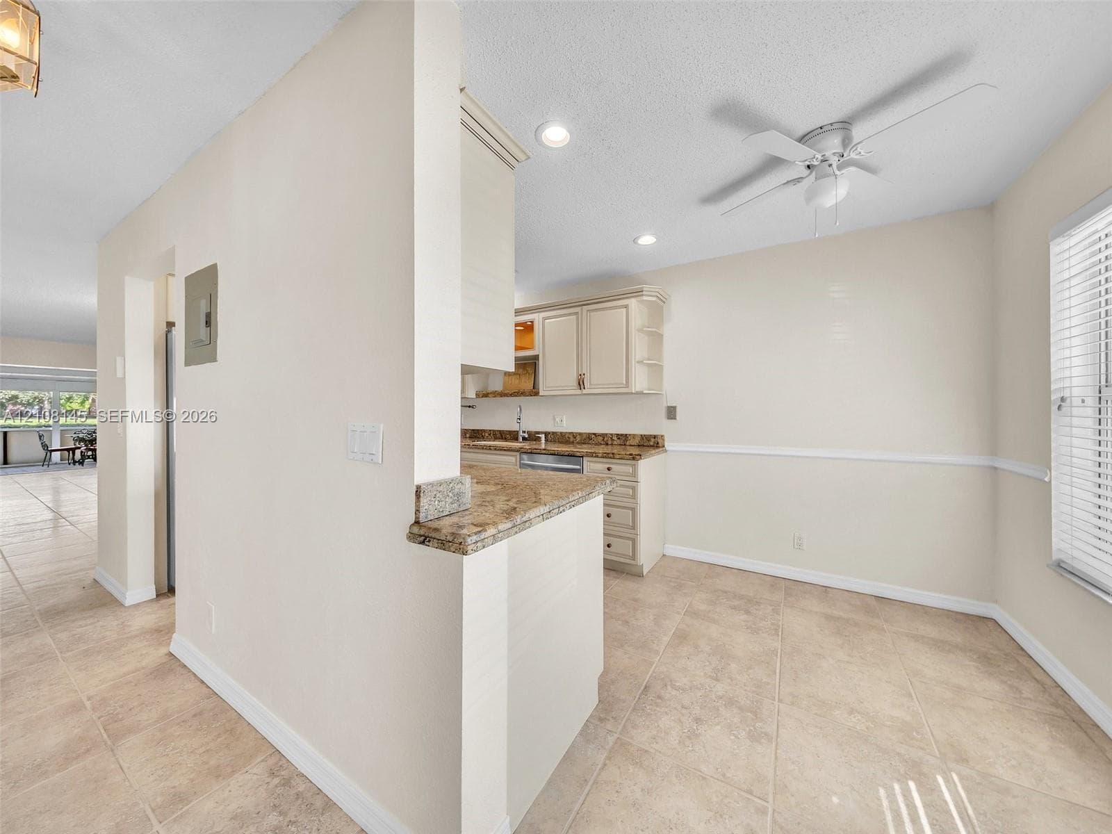 Kitchen featuring cabinetry with stone-surface countertops, tile flooring, recessed lighting, and a ceiling fan