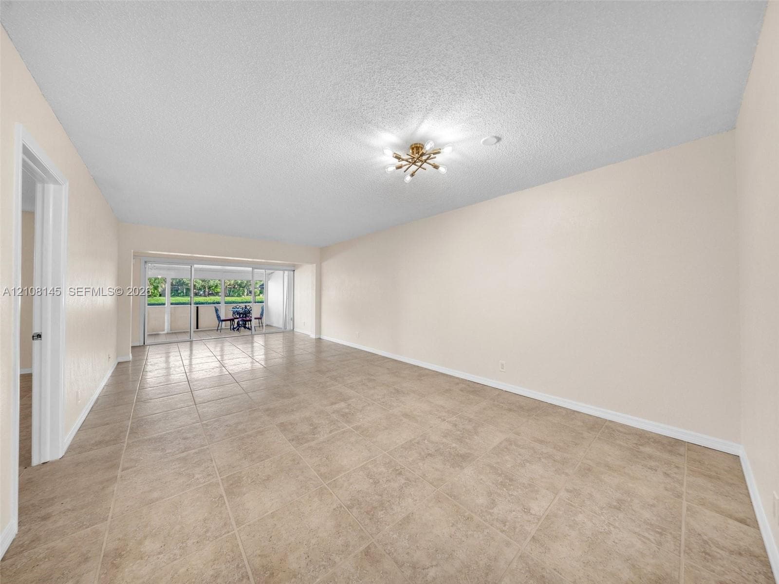 Open living space featuring large-format tile flooring, a multi-arm flush-mount light fixture, and floor-to-ceiling sliding glass doors