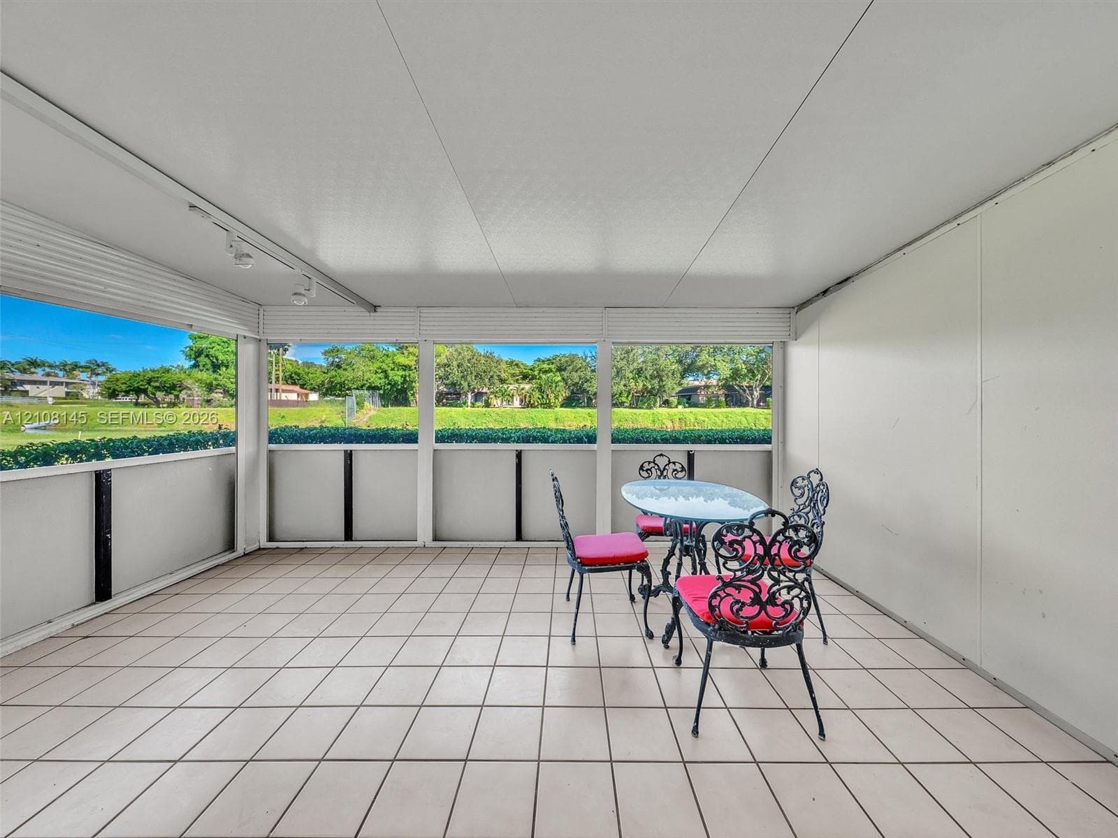 Enclosed patio featuring neutral tile flooring, screen wall panels, and overhead track lighting