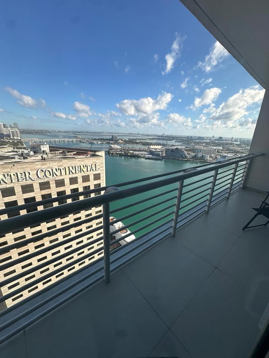 Private balcony featuring large-format tile flooring and a horizontal metal railing overlooking the water