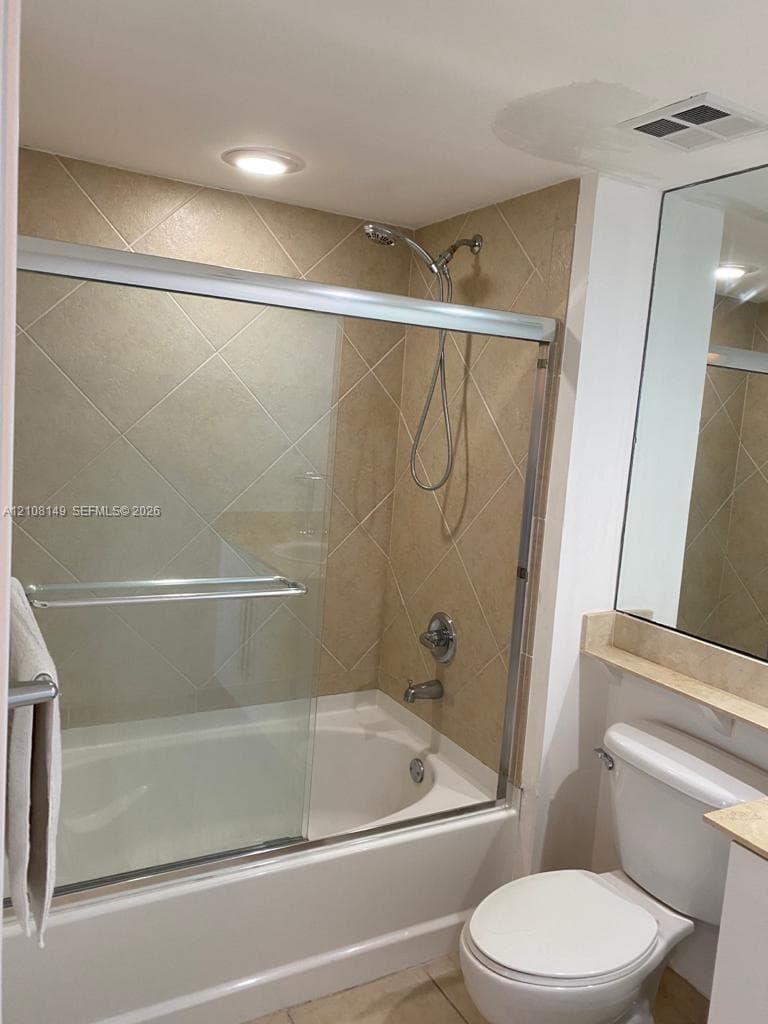 Bathtub and shower combination featuring diagonal wall tile, sliding glass enclosure, chrome fixtures, and recessed lighting