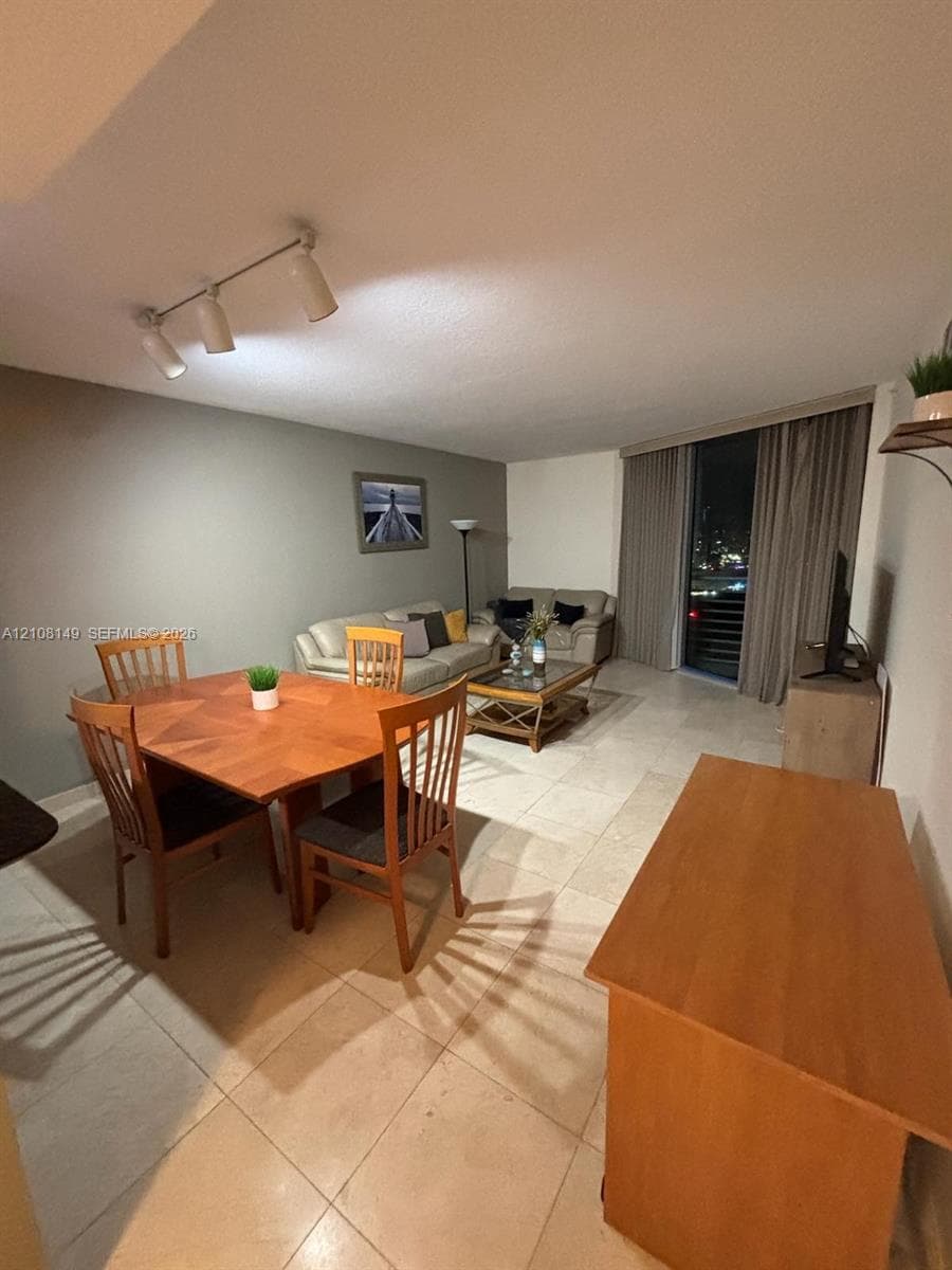 Open-concept interior featuring oversized tile flooring, recessed track lighting, and floor-to-ceiling window treatments