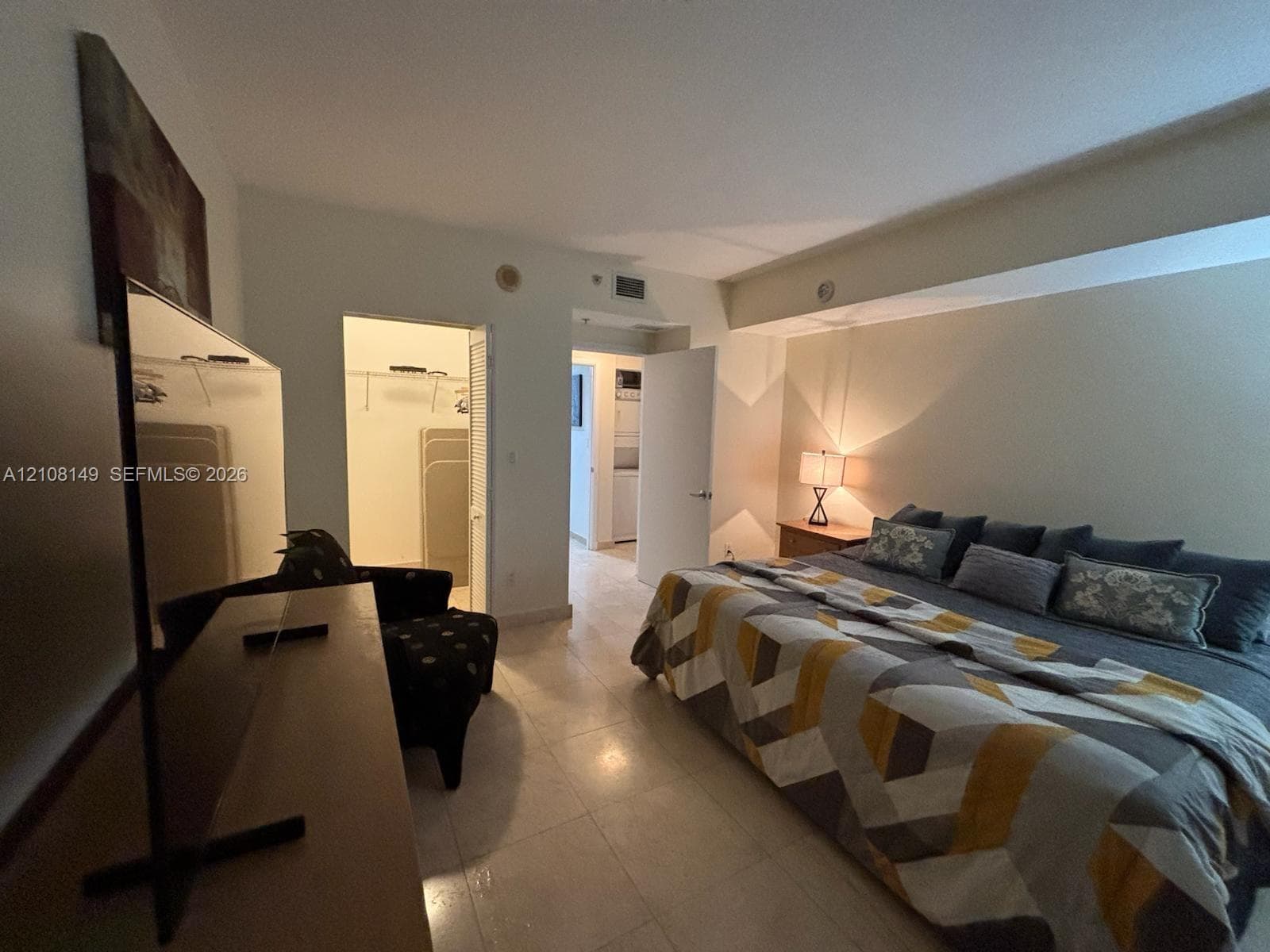 Neutral tile flooring, walk-in closet with built-in shelving, and recessed ceiling lighting