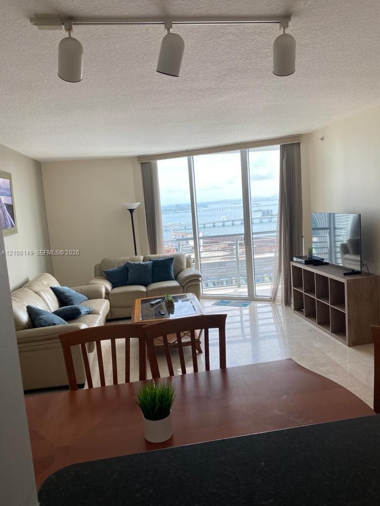 Floor-to-ceiling windows featuring panoramic water and bridge scenery, polished stone-finish flooring, and adjustable multi-directional track lighting