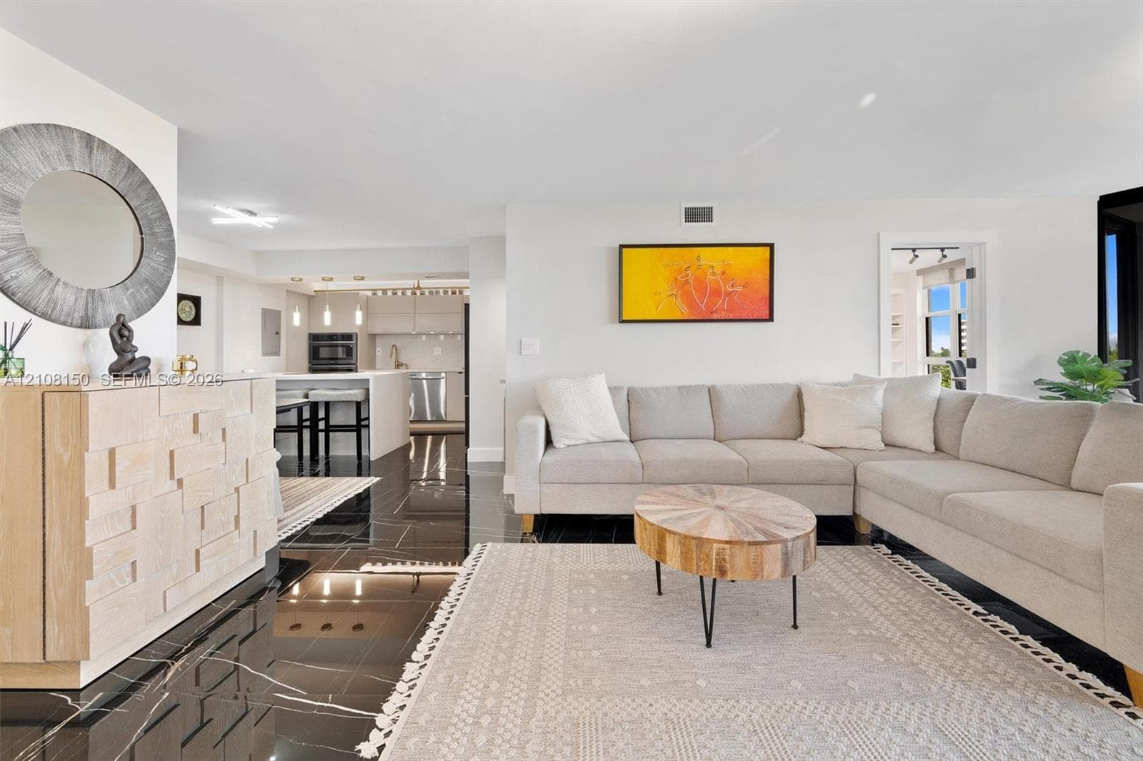 Open-concept interior featuring large-format polished dark stone flooring, recessed lighting, and kitchen cabinetry with integrated stainless steel appliances