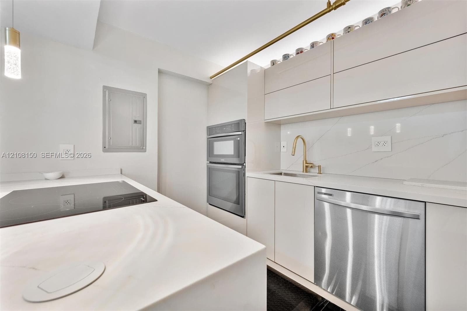Sleek kitchen featuring high-gloss cabinetry, stone-finish countertops, a gold-tone faucet, a stainless steel dishwasher, and a built-in double oven