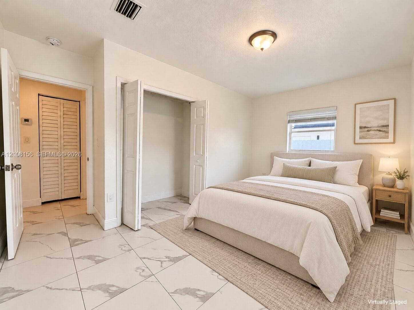 Large-format tile flooring with a light veined pattern, dual closets with bi-fold louvered doors, and a neutral color palette