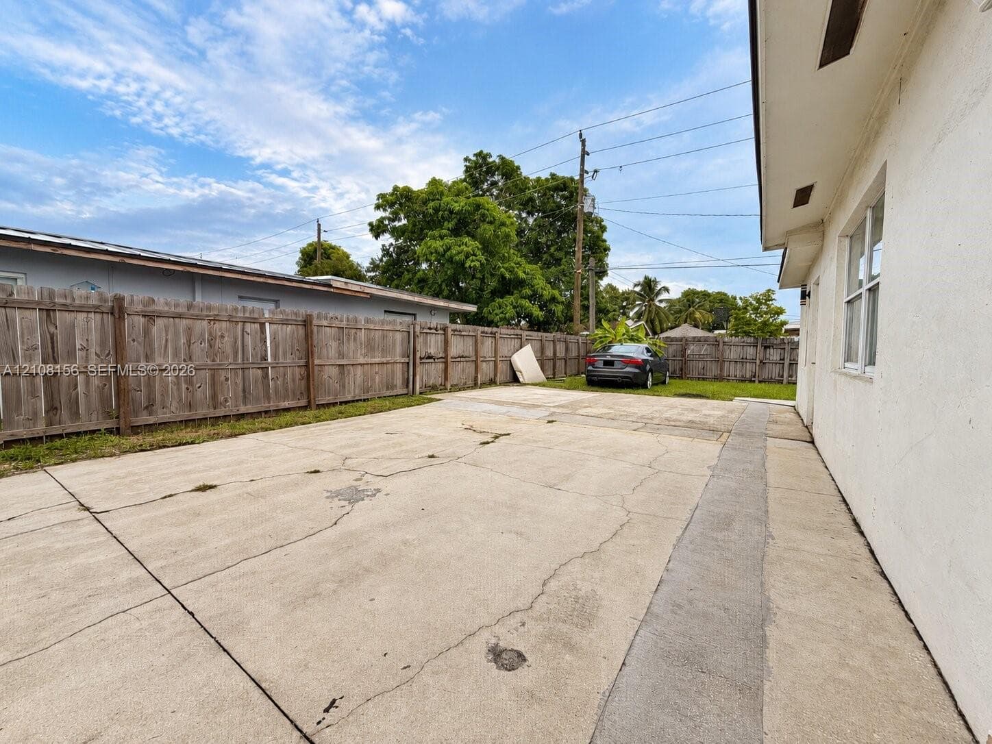 Exterior concrete driveway featuring a wood-panel perimeter fence