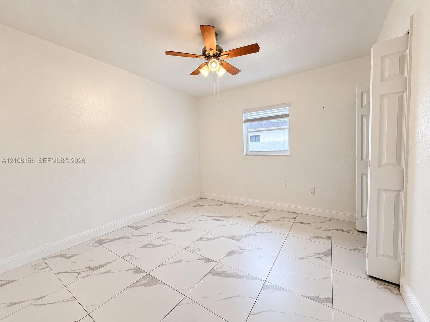 Interior room featuring large-format tile flooring with a neutral pattern, high-contrast ceiling fan with integrated lighting, and white six-panel closet doors