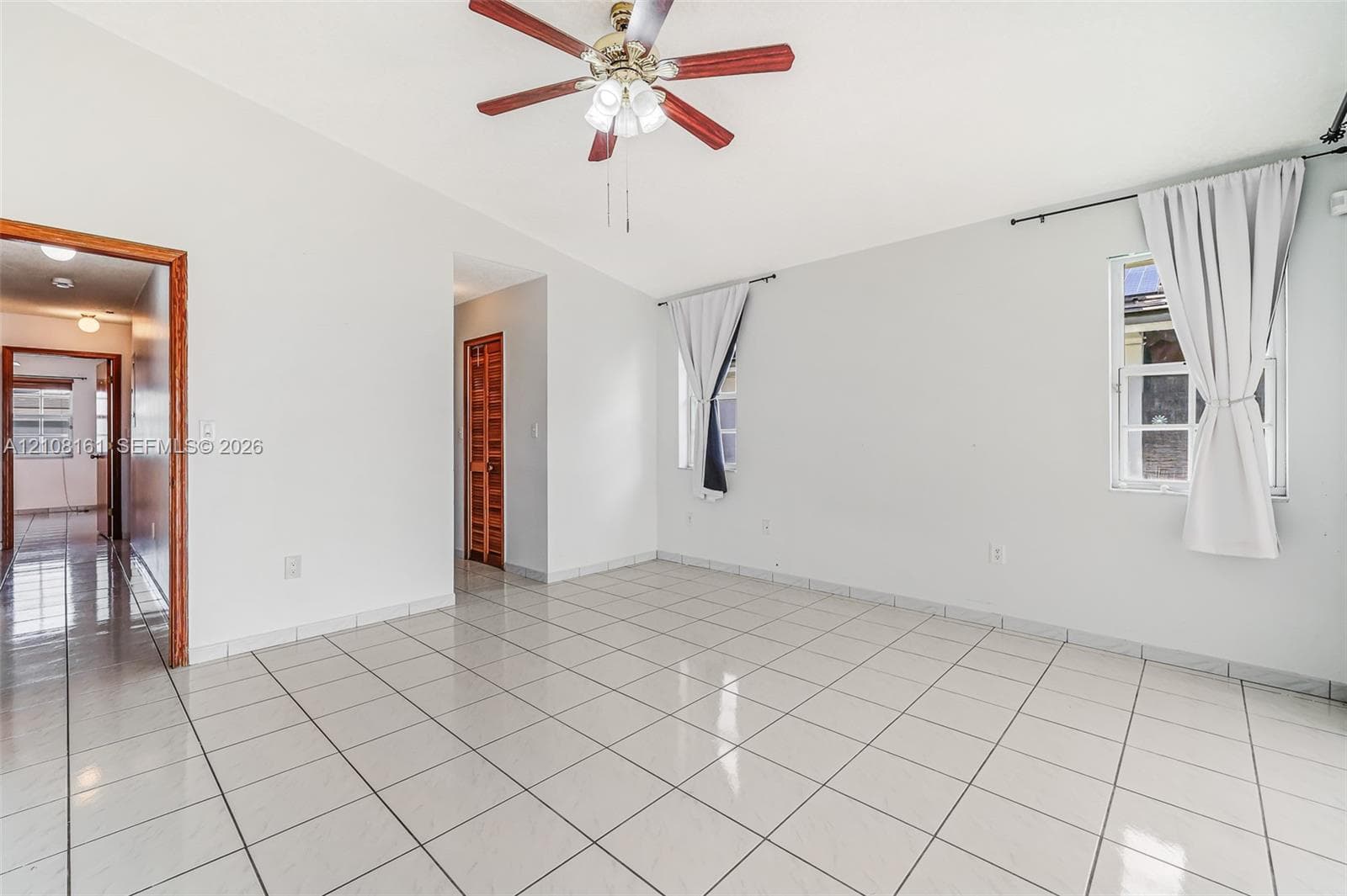 Interior space featuring light-colored tile flooring, vaulted ceilings, and a central ceiling fan with multi-light fixture