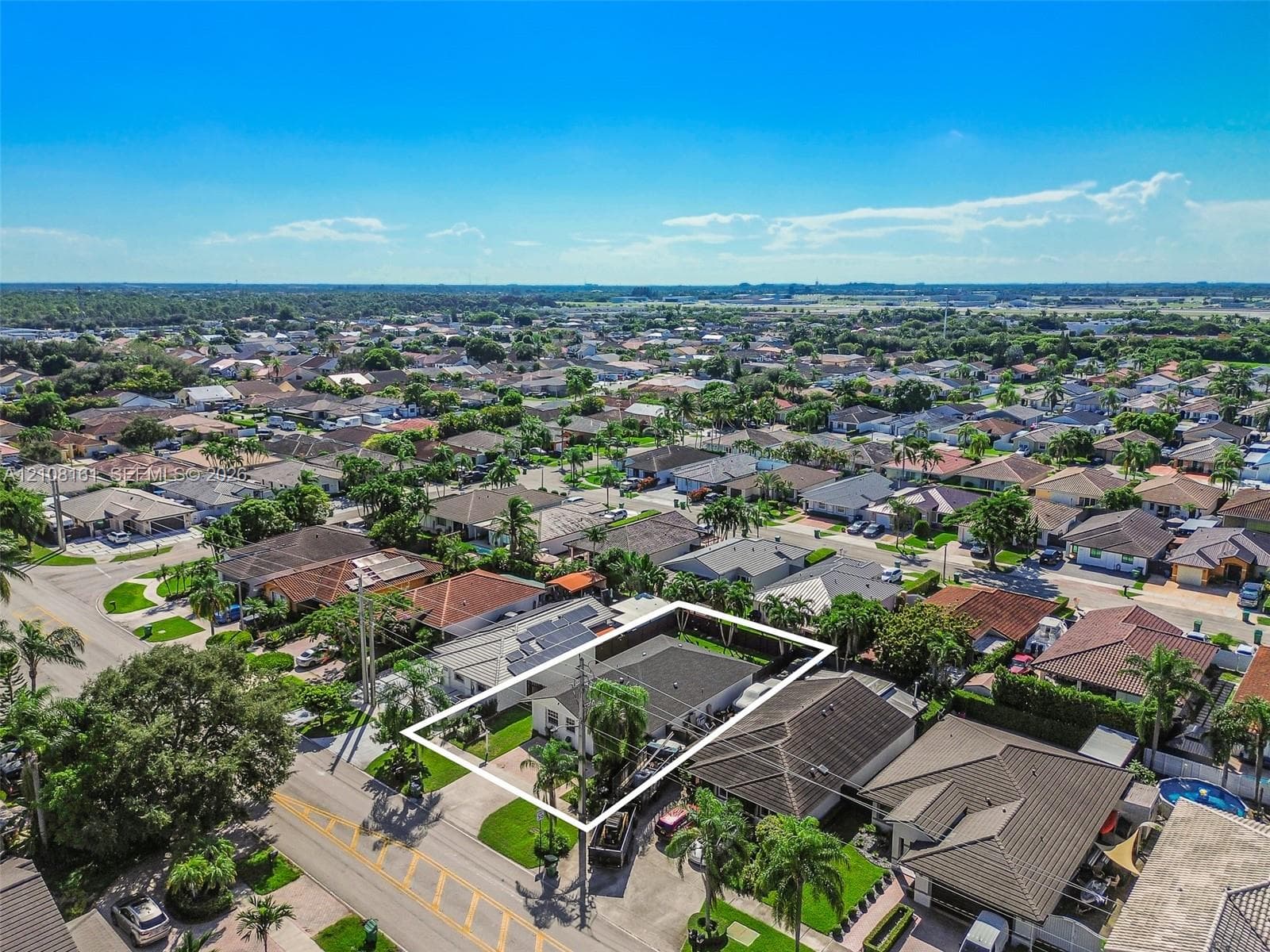 Aerial perspective of property featuring a fenced perimeter, solar panels, and manicured landscaping