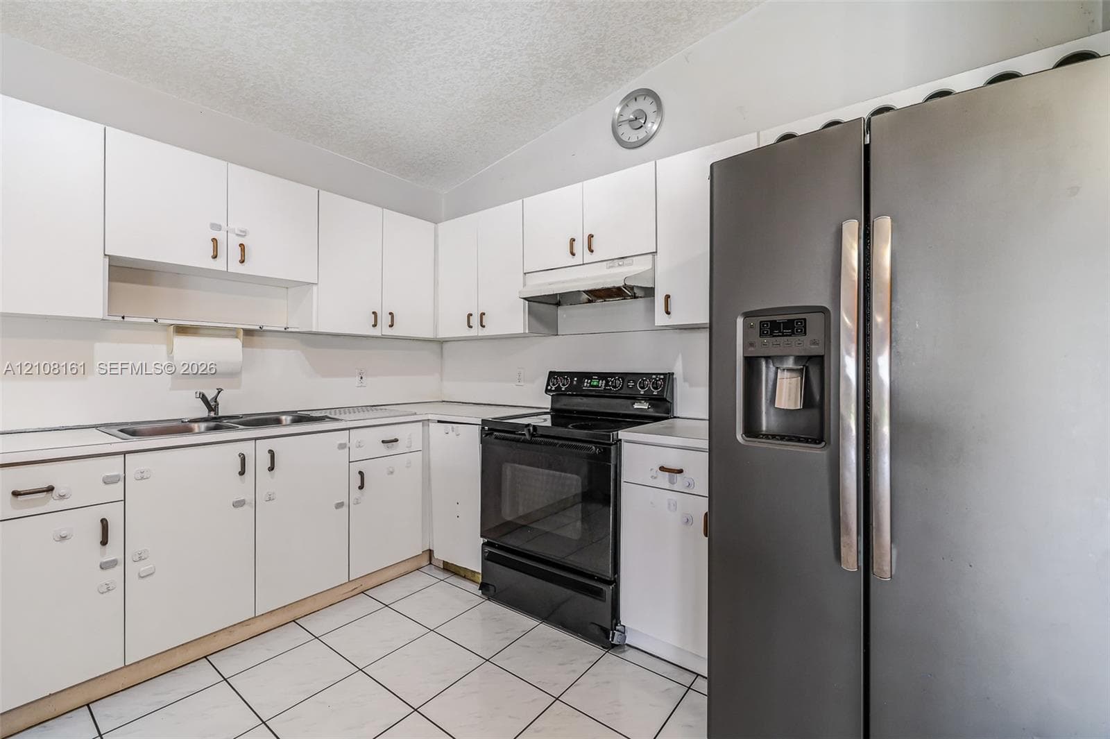 Kitchen featuring white cabinetry, stainless steel appliances, a dual-basin sink, and tile flooring