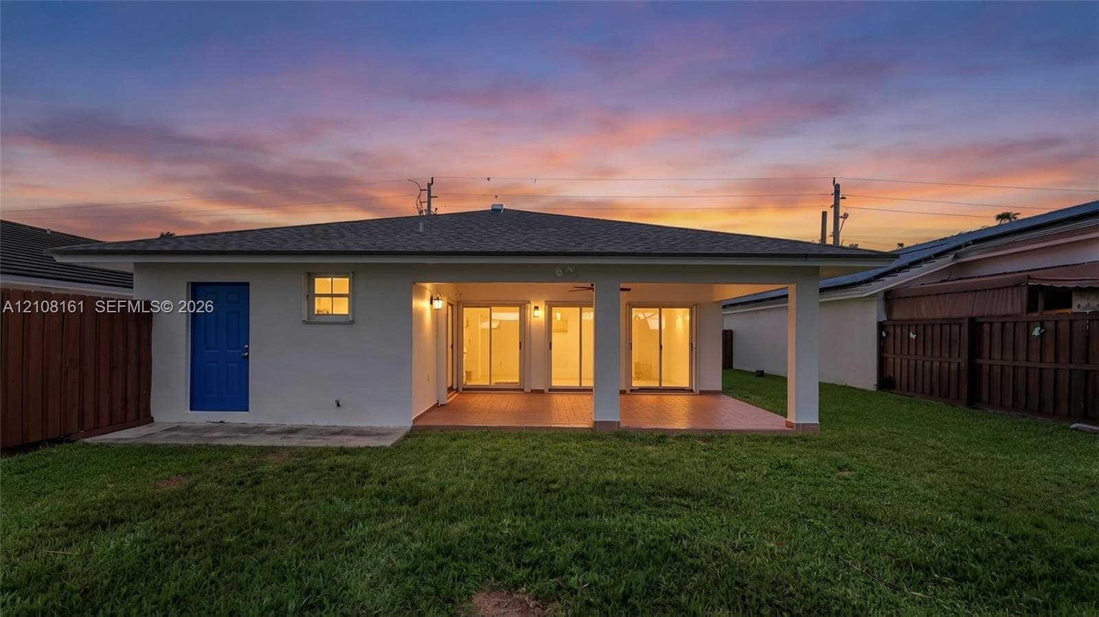 Rear exterior featuring a covered patio, tiled flooring, glass sliding doors, and privacy fencing