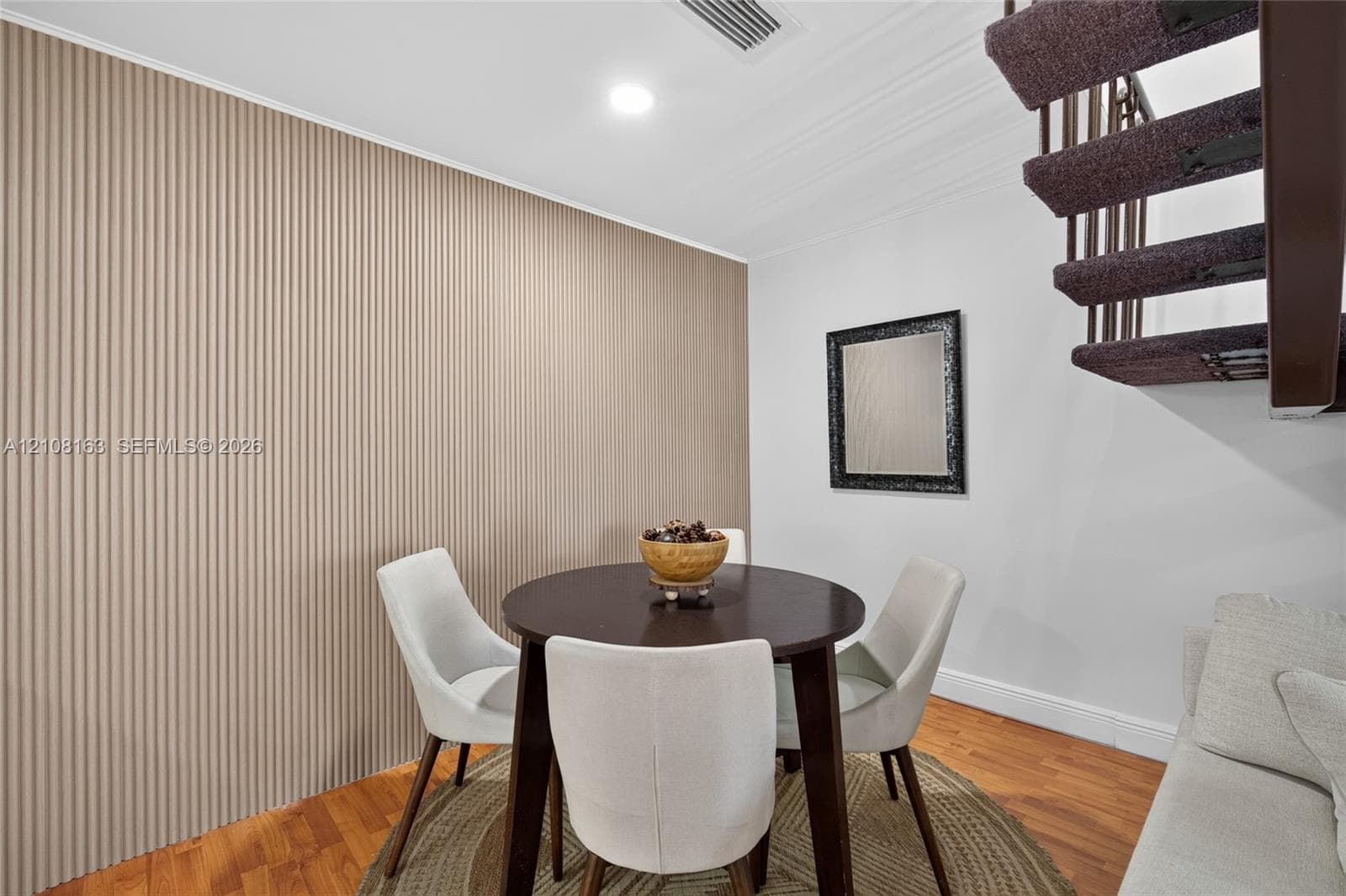 Textured accent wall, wood-finish flooring, and floating staircase with open risers