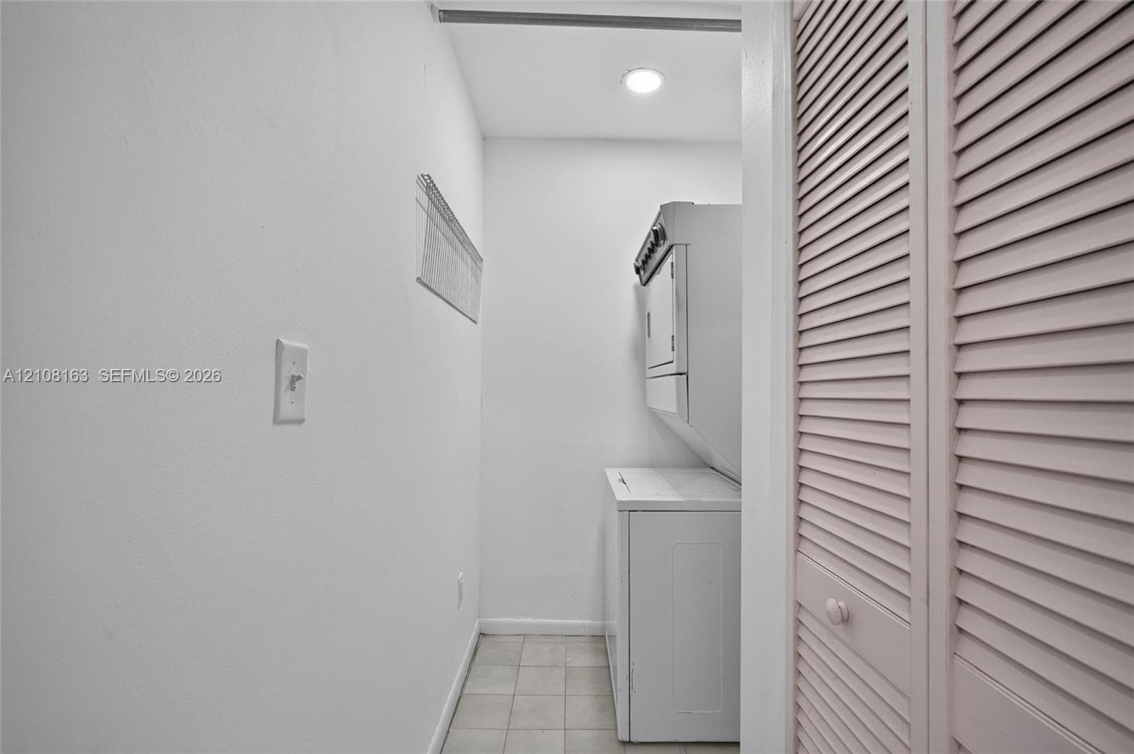 Utility space featuring tile flooring, recessed lighting, and louvered closet doors